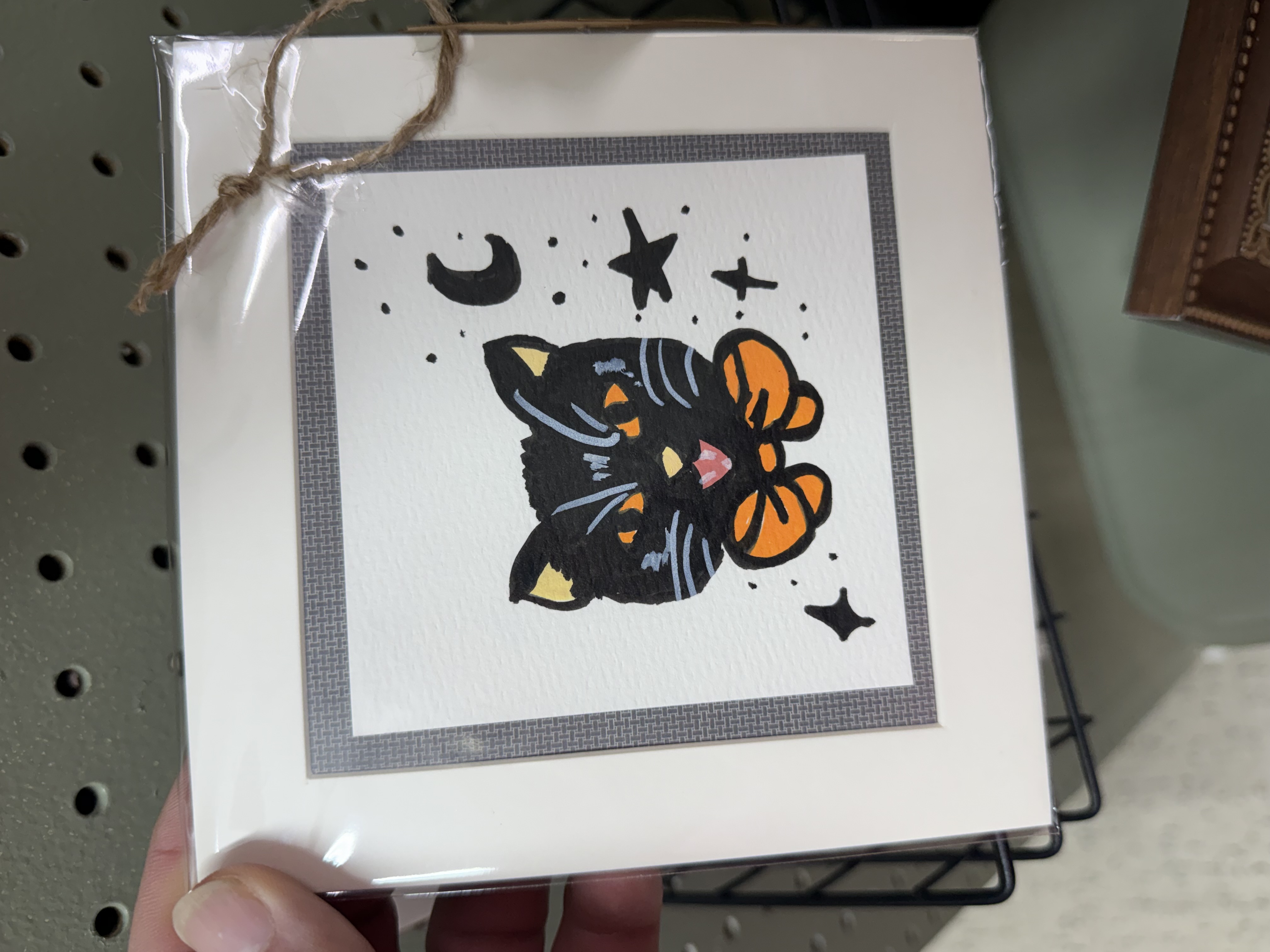 Bella Hale's matted black cat artwork with an orange bow, moon, and stars