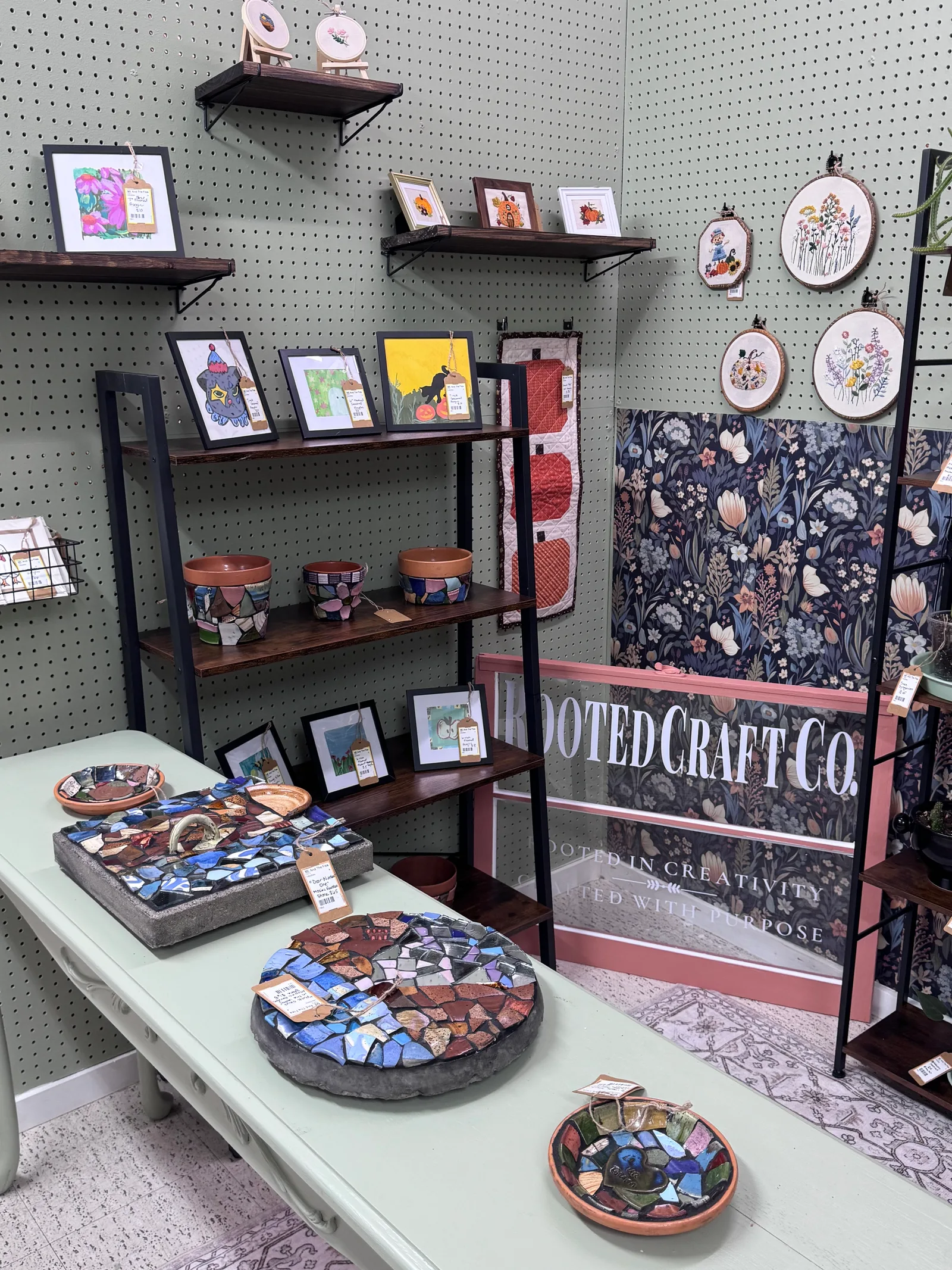Framed drawings and botanical embroidery displayed at Rooted Craft Co